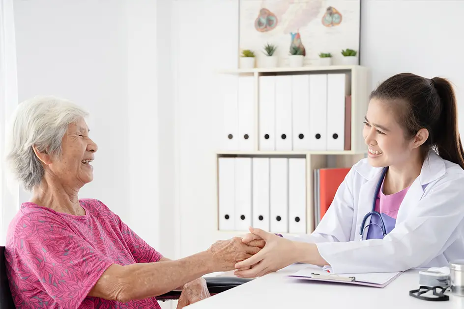 An older patient happily meeting with a doctor in a doctors office.