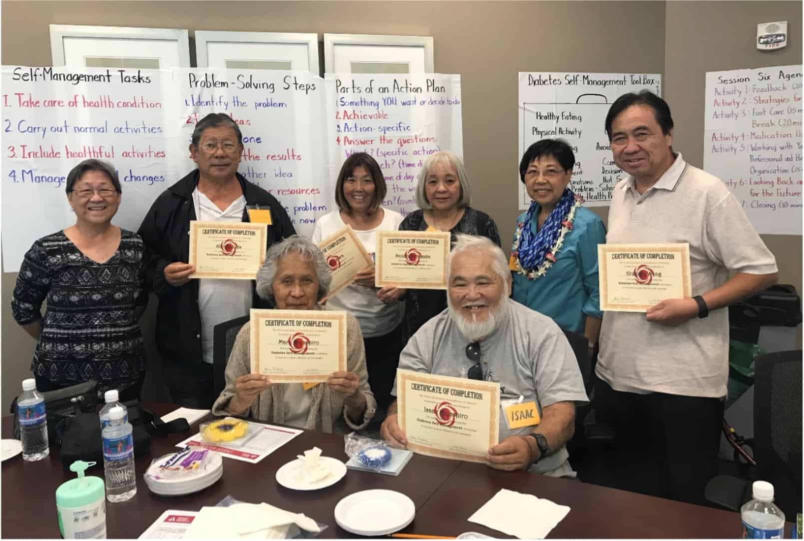 A group of older people holding up certificates of completion.