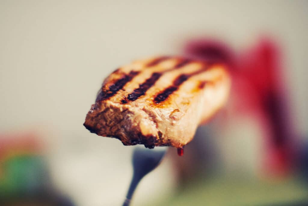 A juicy grilled steak on a fork.