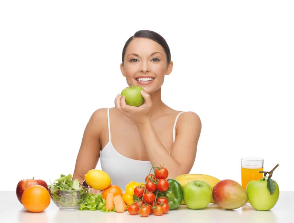 healthy woman with lot of fruits and vegetables in front